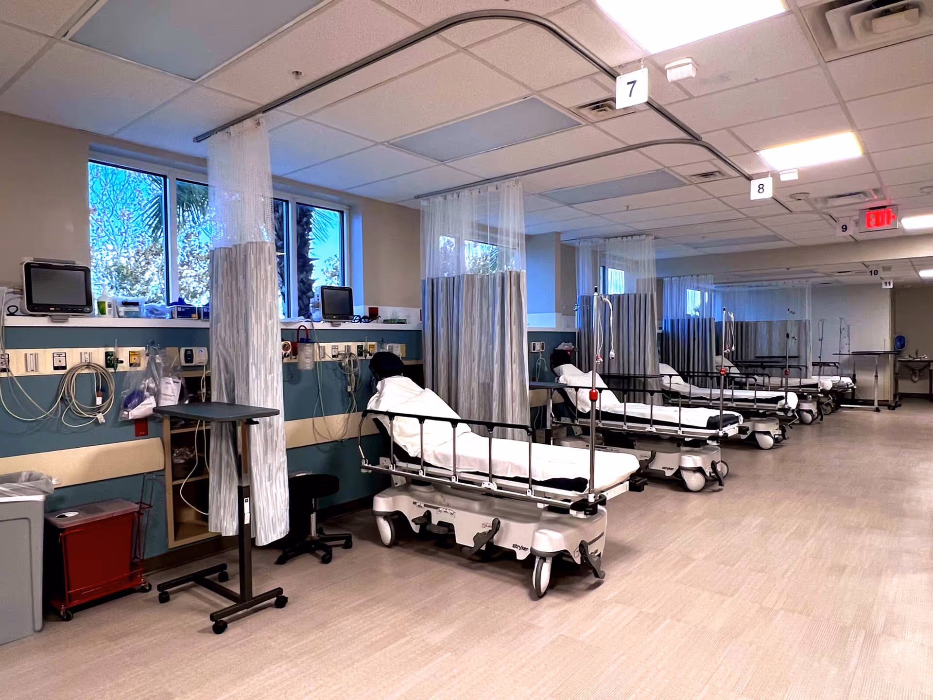 Hospital ward with multiple patient beds separated by curtains and medical equipment.