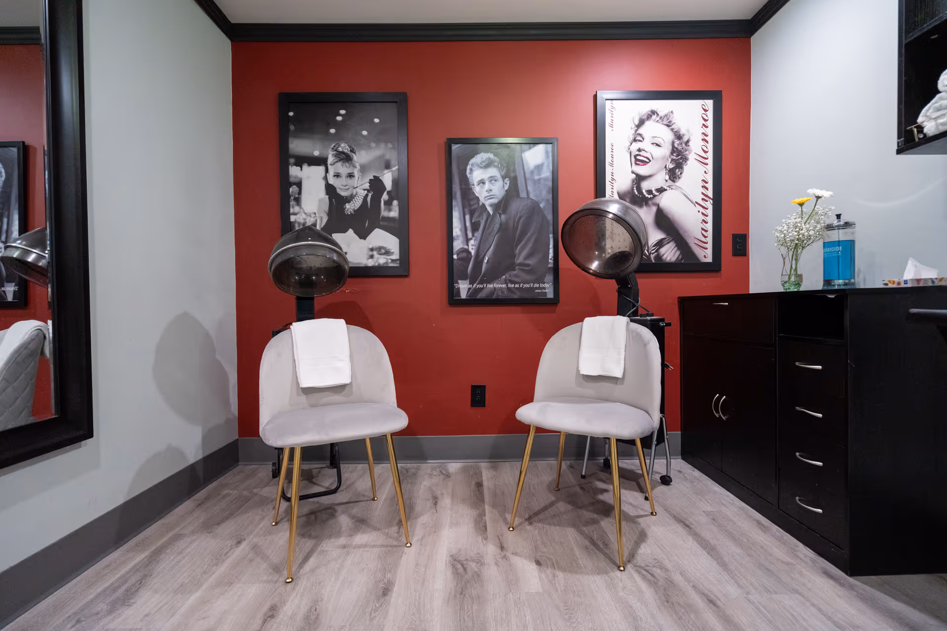 A salon area with two white seats, hair wash basins, and a red accent wall.