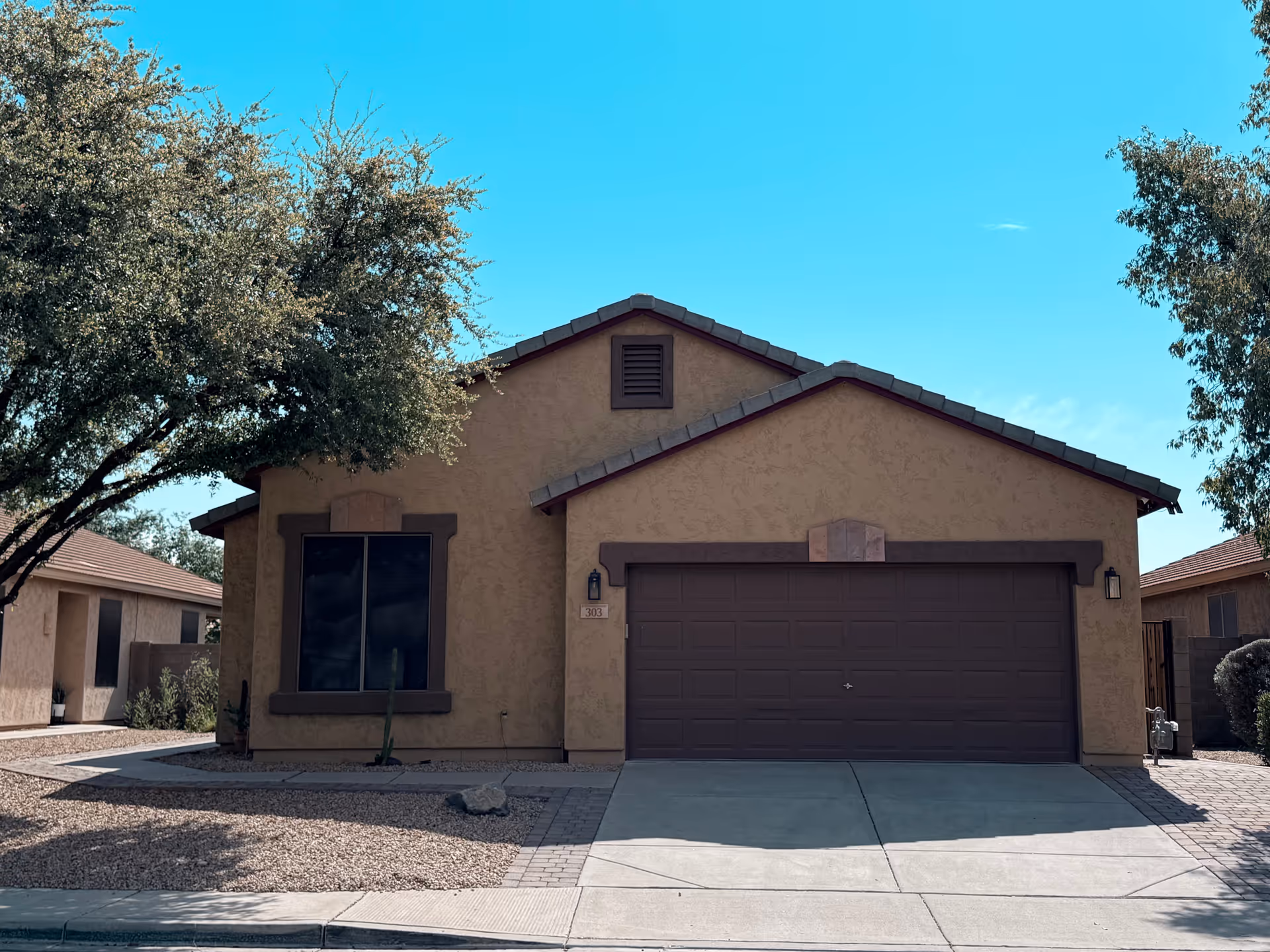 Front view of a tan assisted living home with a two-car garage and desert landscaping.
