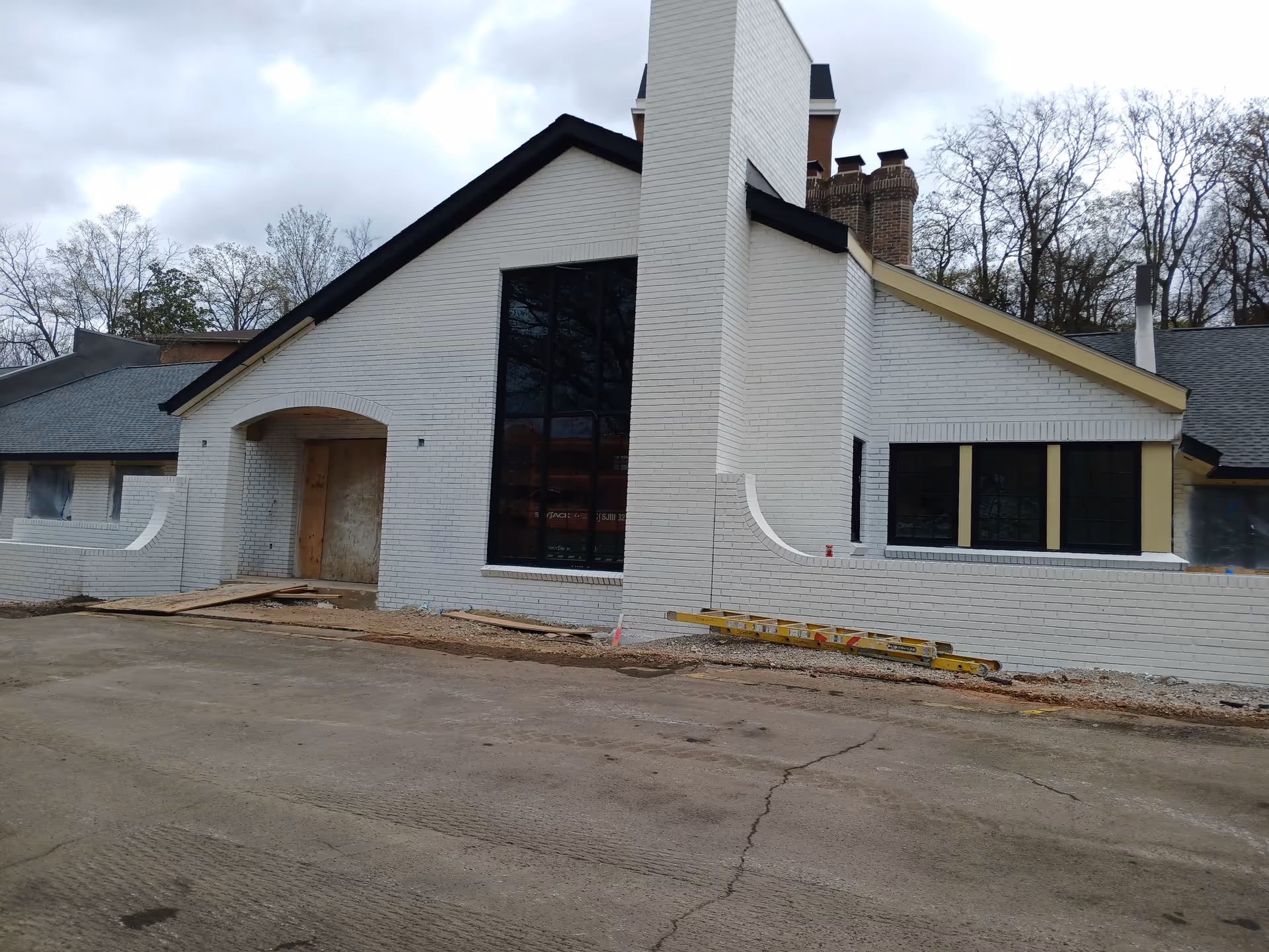 White brick building under construction with a large window and front entrance.