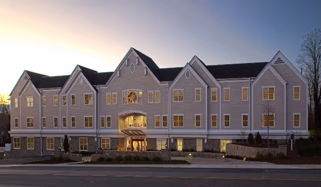 Exterior view of Maplewood at Darien senior living building at dusk with multiple windows.