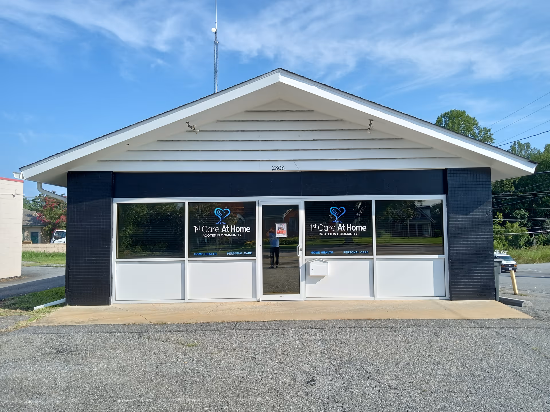 Small storefront building labeled 1st Care At Home with glass doors and windows