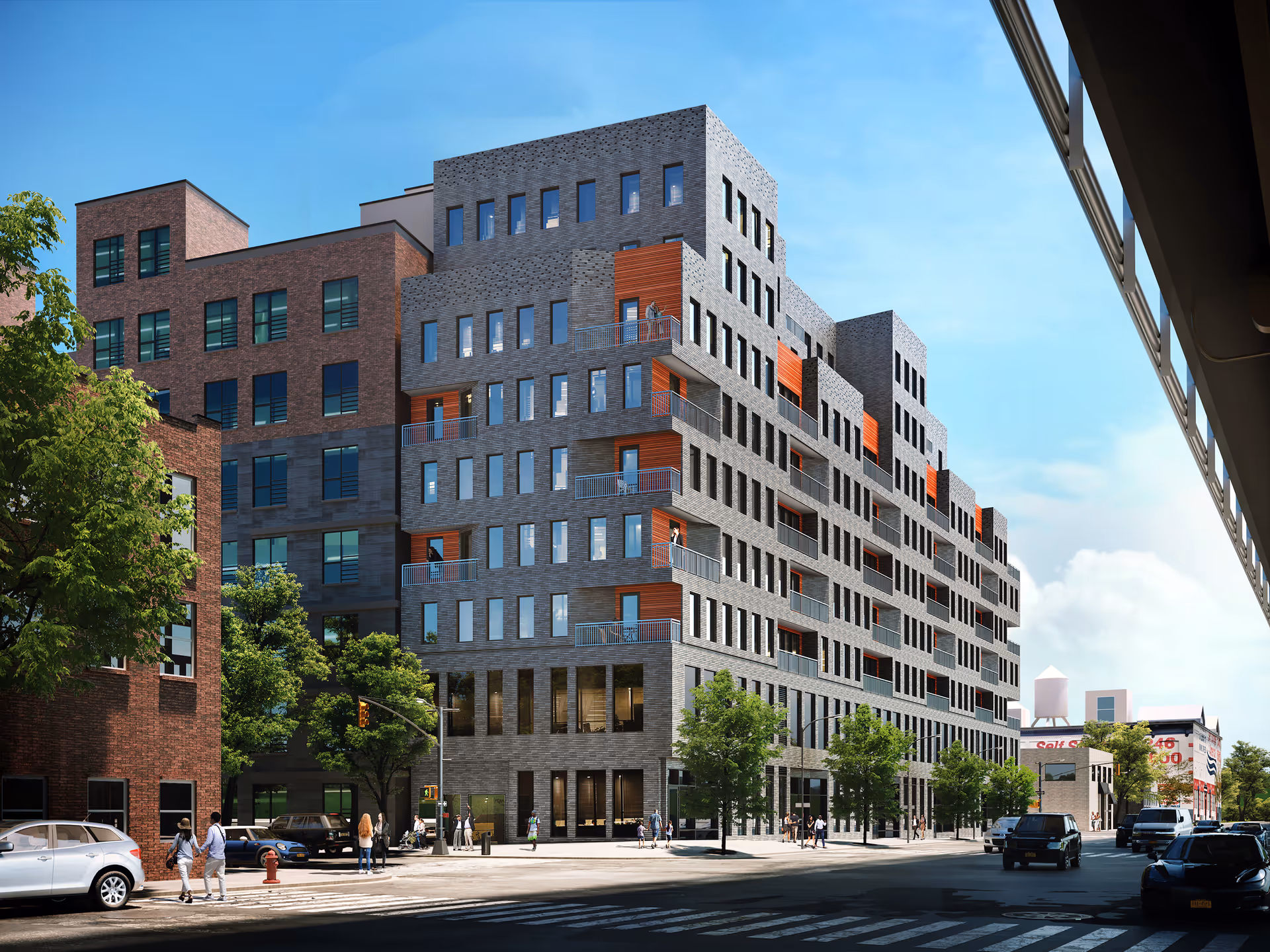 Modern multi-story brick-gray building with balconies lining a busy city street.