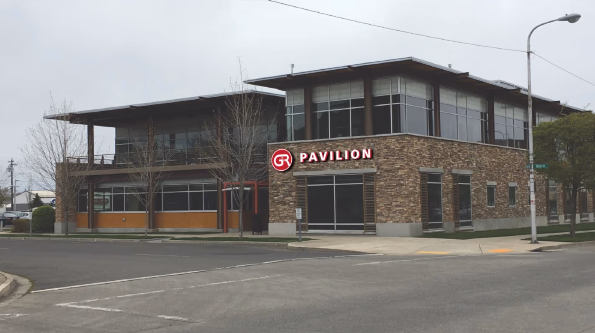 A modern two-story building with stone facade and GR Pavilion signage on a street corner.