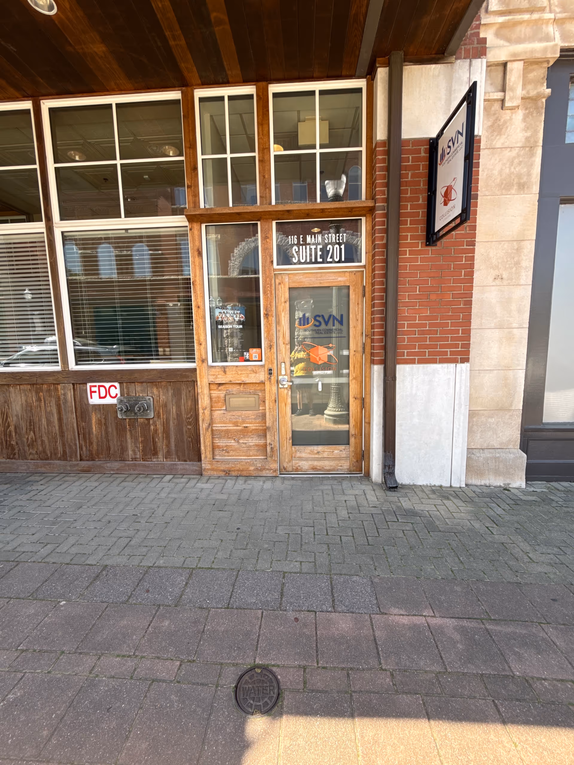 Wood-framed glass storefront door labeled Suite 201 on brick exterior.
