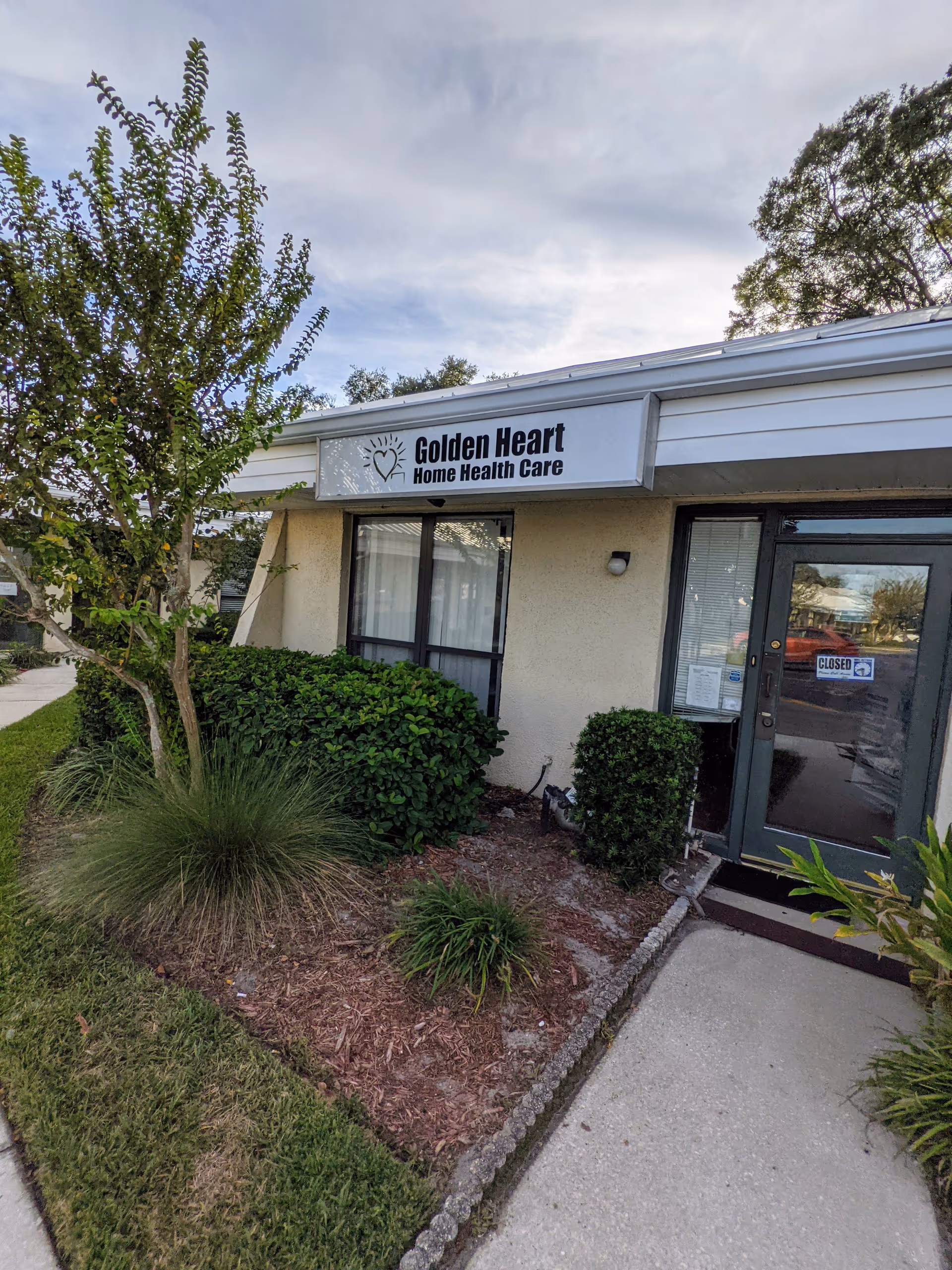 Exterior view of Golden Heart Home Health Care building with entrance door and landscaped surroundings.