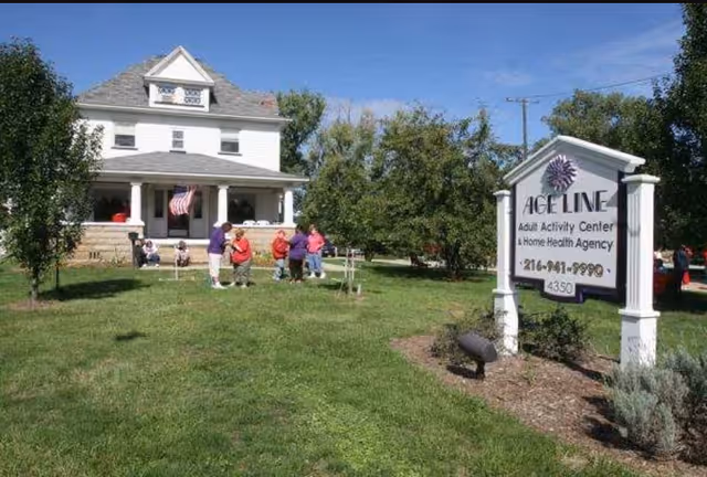 Exterior view of Age Line Home Health and Activity Center with people gathered on the lawn.