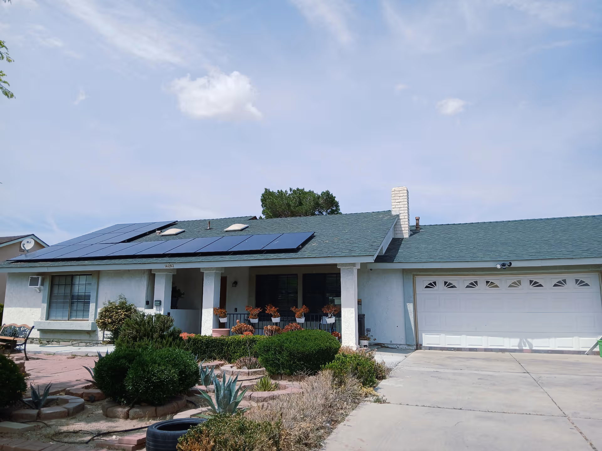 Single-story senior living facility front view with a two-car garage and solar roof panels.