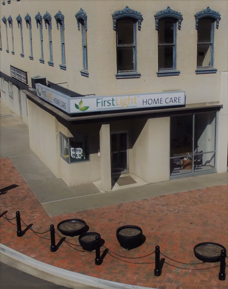 A storefront labeled FirstLight Home Care on a beige building with brick sidewalk.