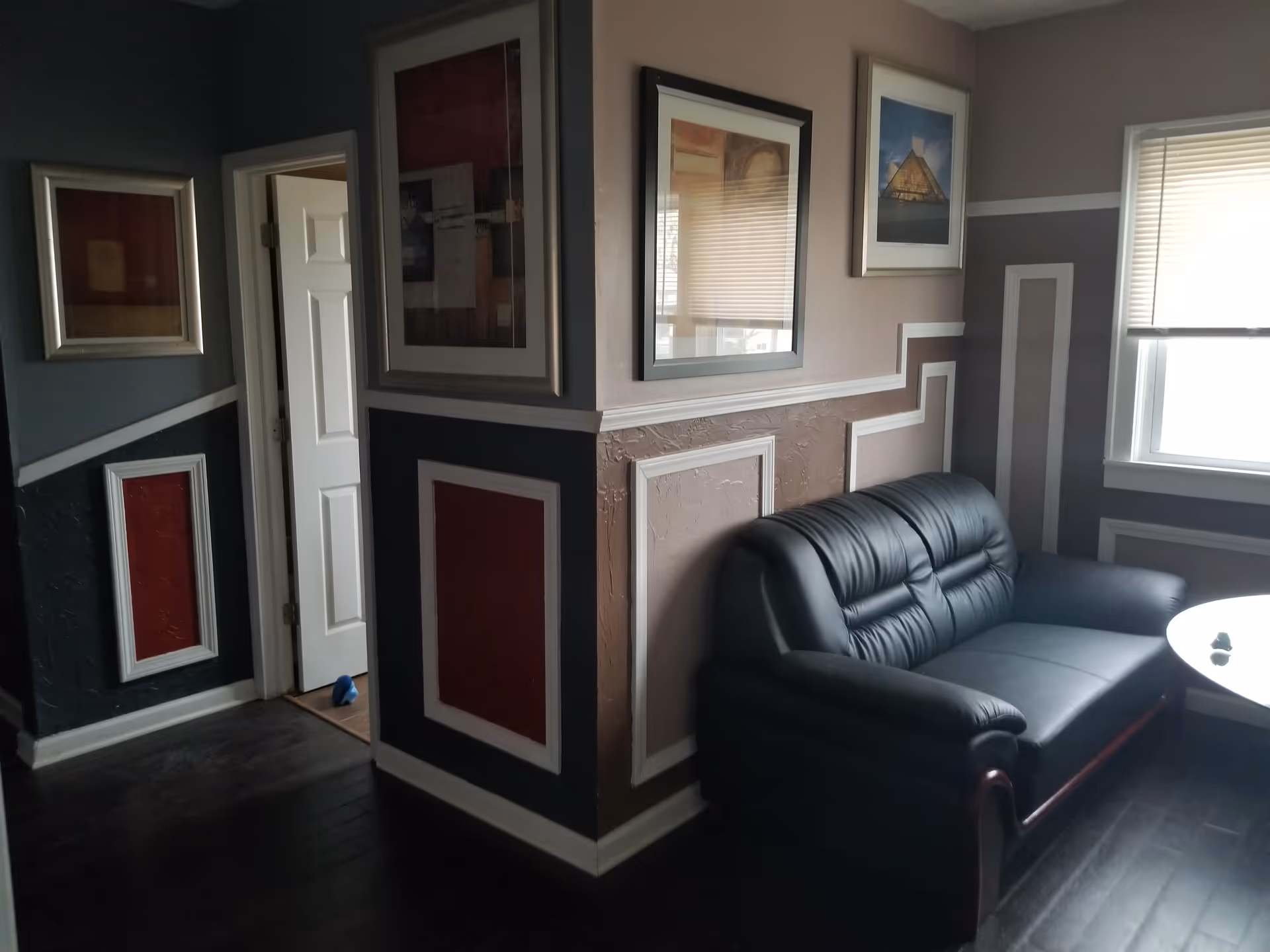 Cozy living room with leather sofa, framed art, and decorative wall panels.