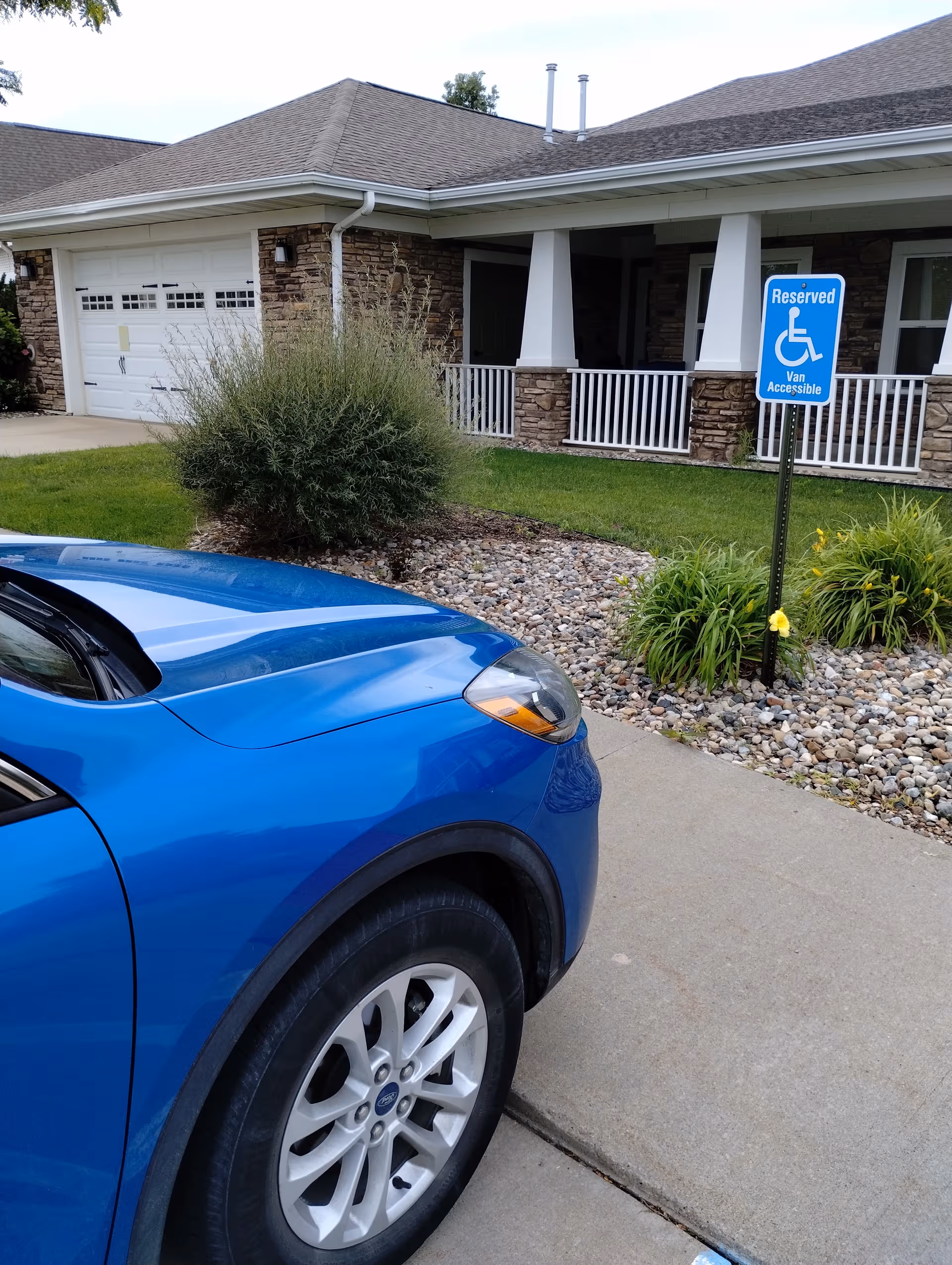 Blue car in driveway in front of Hearthstone Pella facility exterior