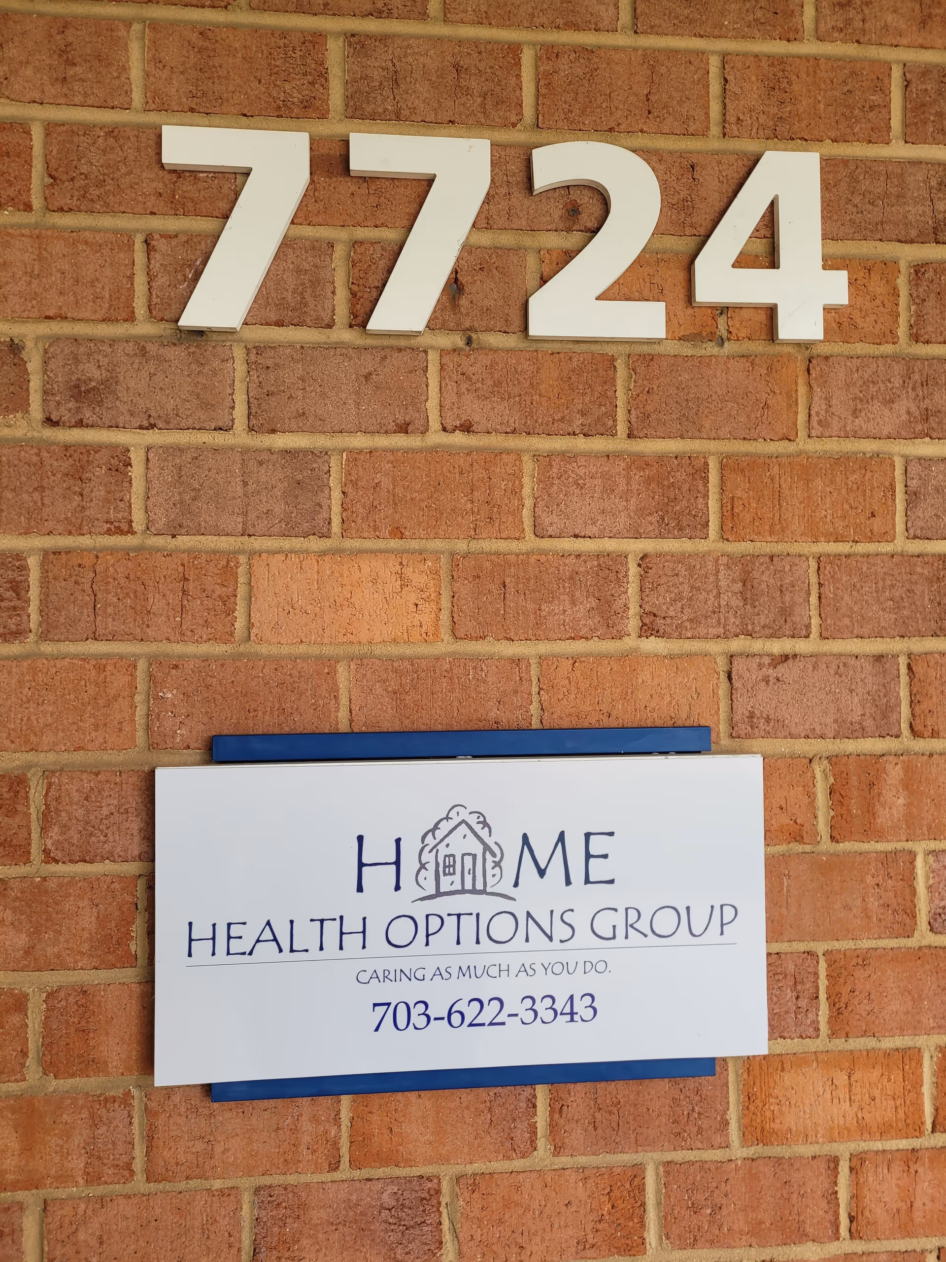 Brick wall with large house numbers 7724 and a sign for Home Health Options Group.