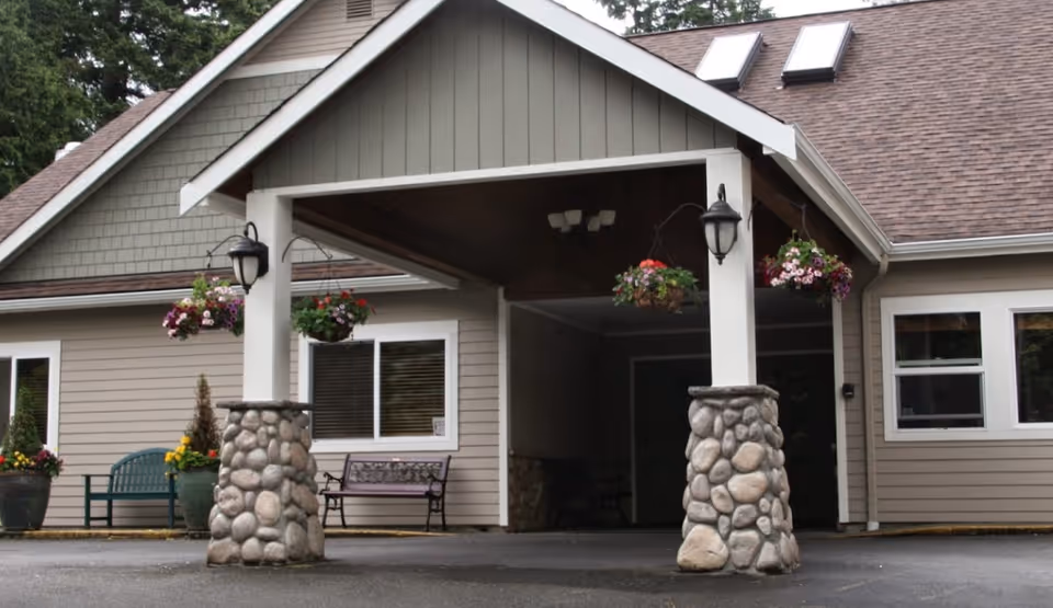 Front view of Peters Creek Retirement Center entrance with stone pillars and hanging flower baskets.