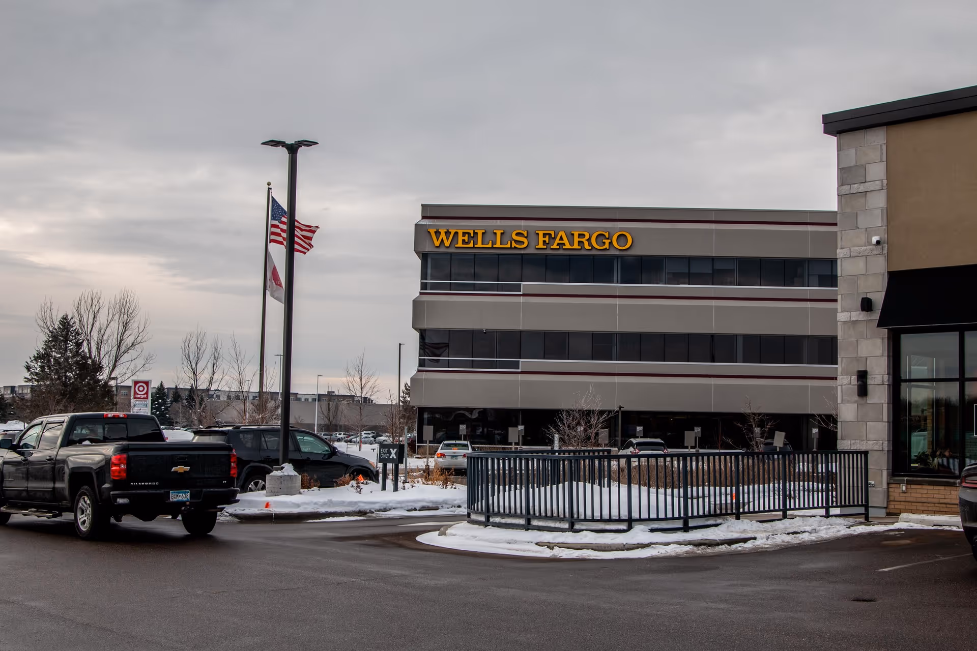 Exterior view of a Wells Fargo building with parked cars and snow.