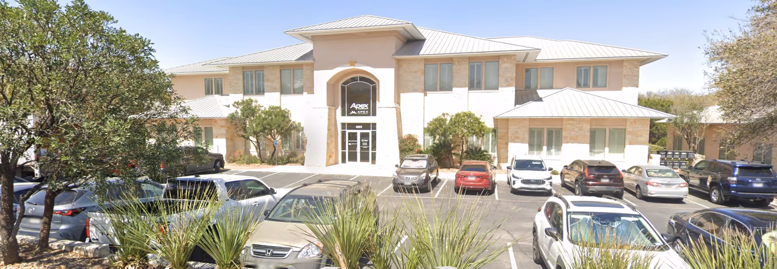Crest Palliative Care building exterior with arched entrance and a parking lot.