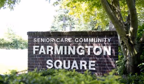 A brick sign reading Farmington Square Senior Care Community, surrounded by trees.