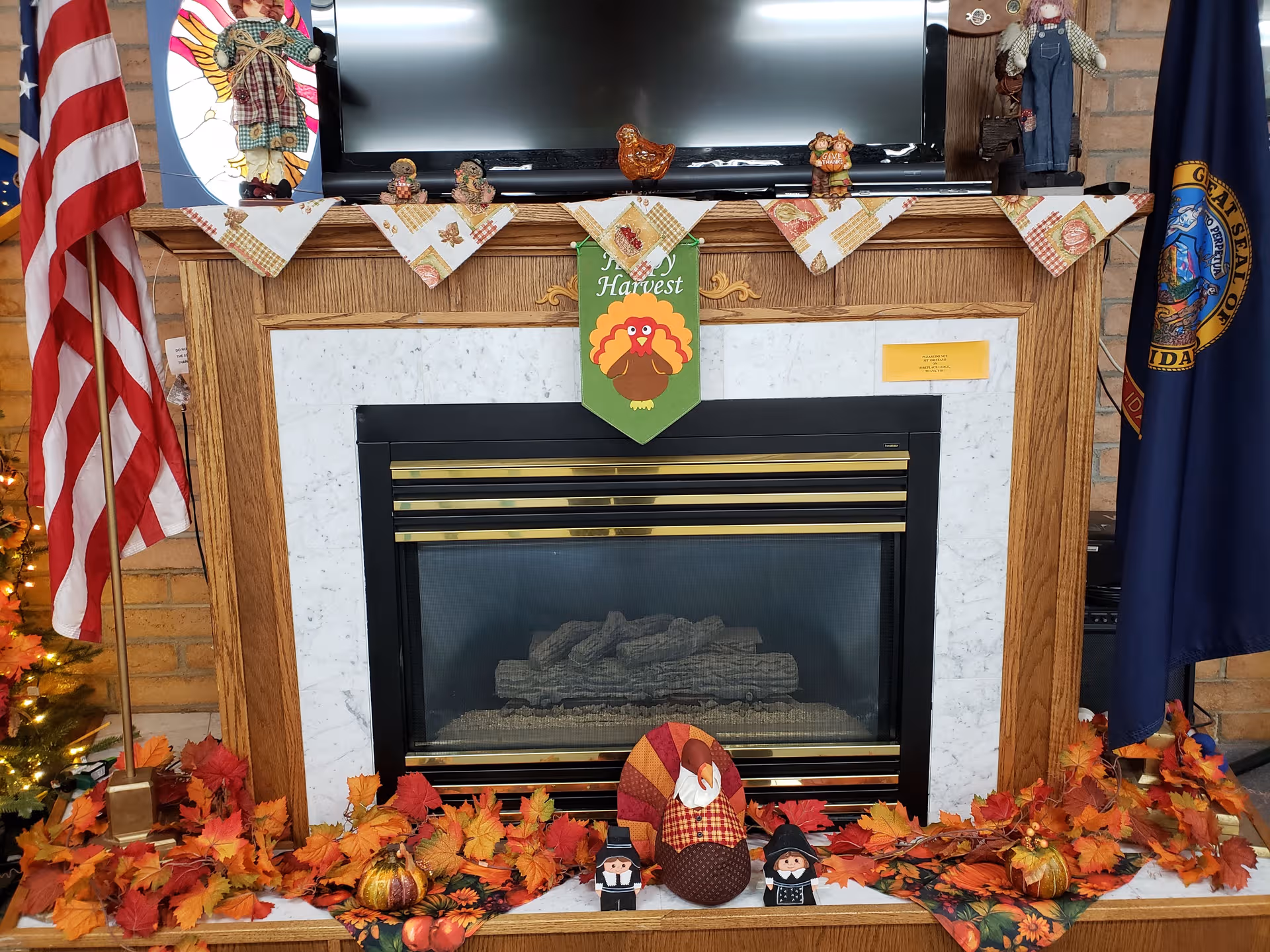 Indoors, a marble-surround fireplace with autumn decorations, flags, and pumpkins.