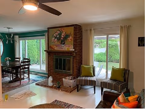 Bright living room with brick fireplace, sliding doors, and striped chairs.