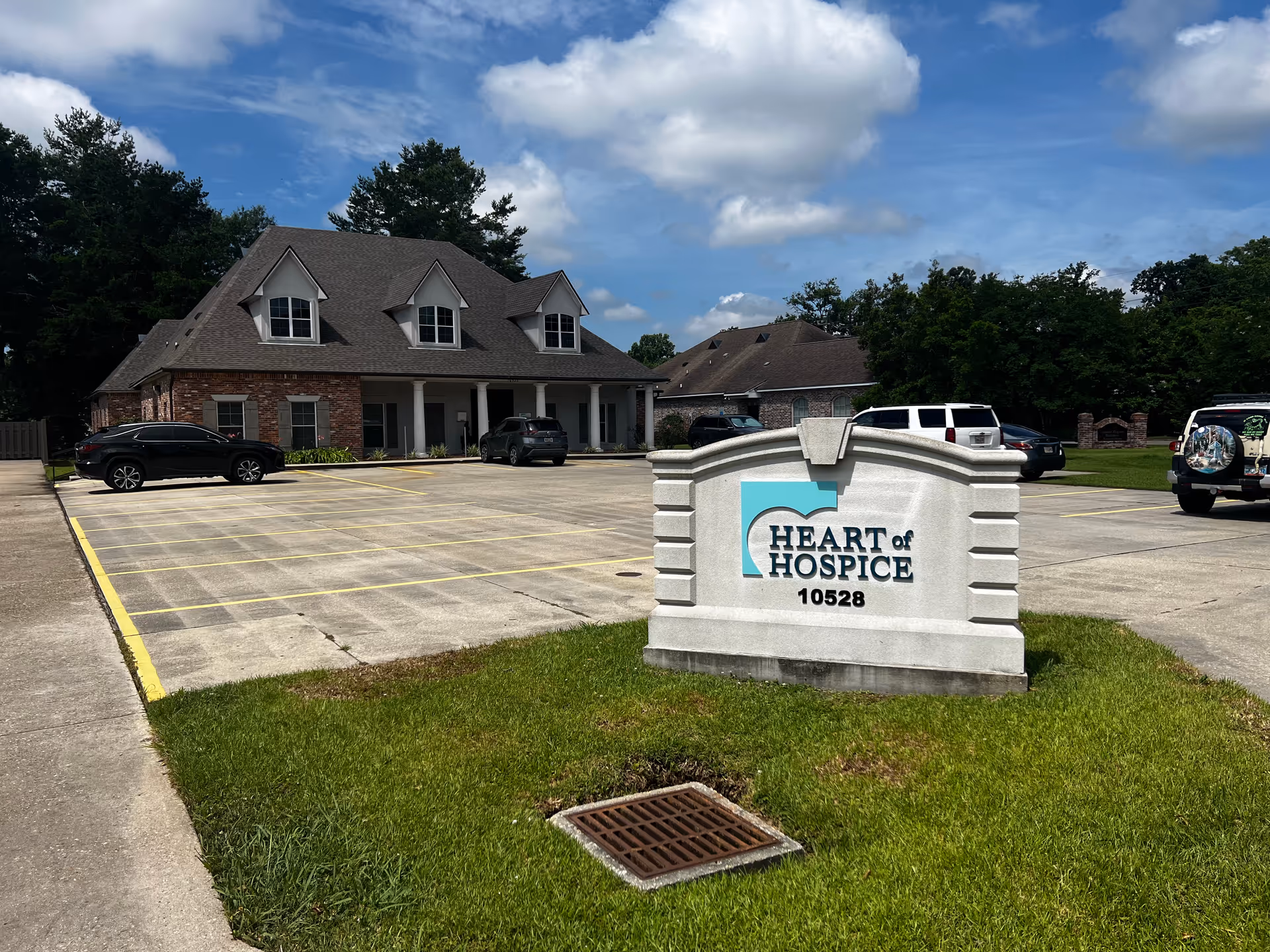 Exterior view of Heart of Hospice facility with a large sign and parking lot.