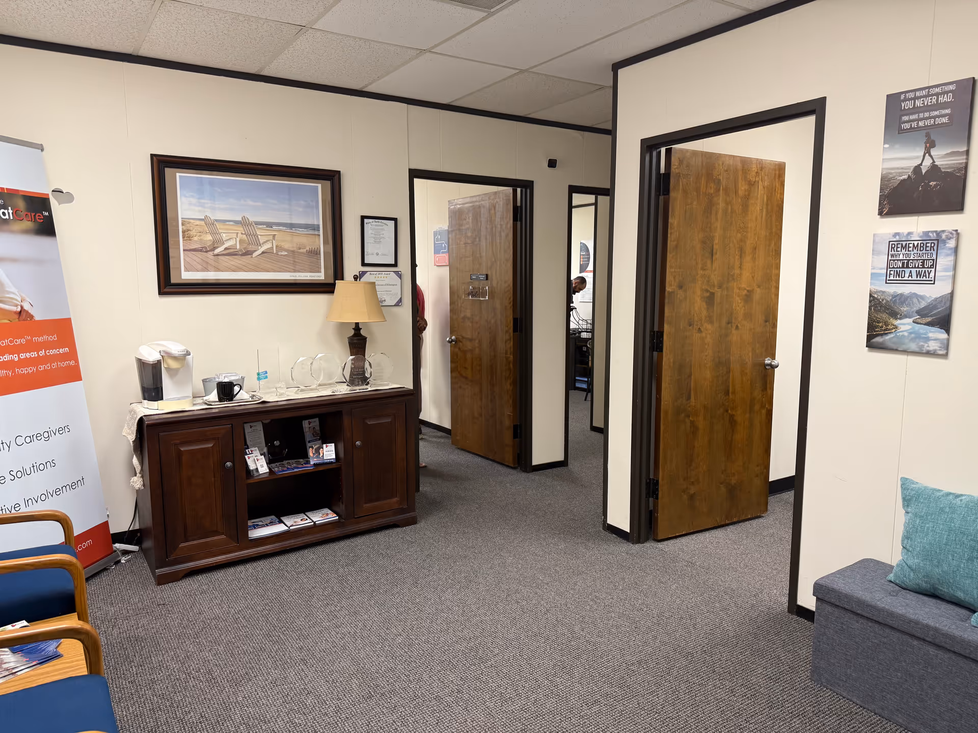 Interior waiting area in senior care facility with coffee station and doors.