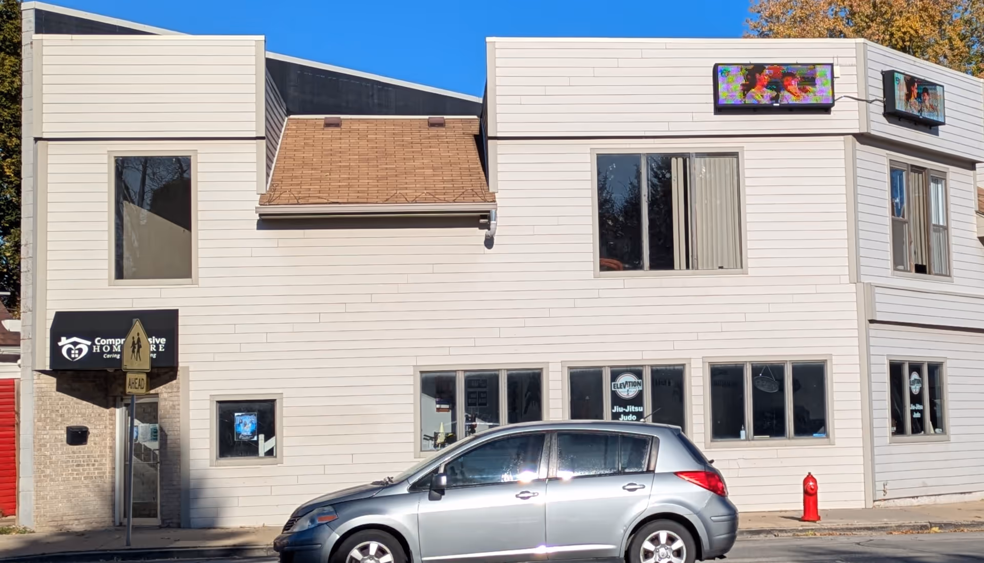 Two-story white building with Comprehensive Home Care signage and a parked silver car.