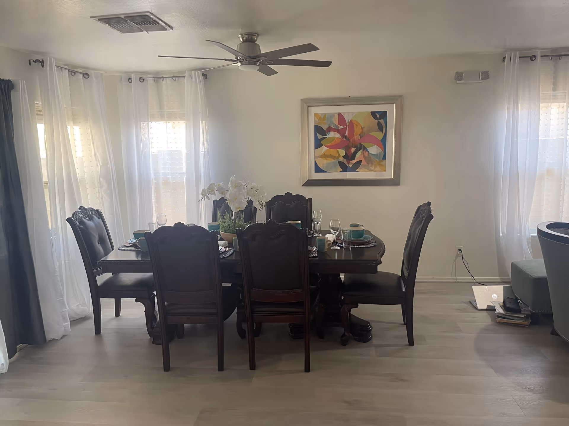 A dark wooden dining table with six chairs set for a meal.