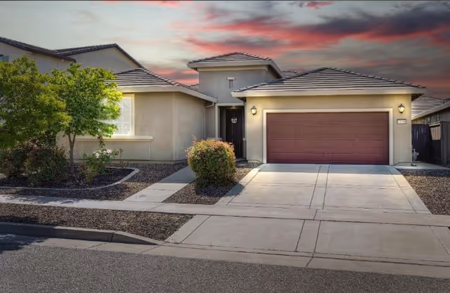 Front exterior of a single-story senior living home with a two-car garage and landscaped yard.