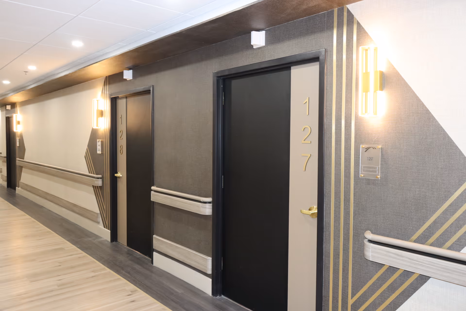 Interior hallway with numbered doors, wall rails, and warm lighting.