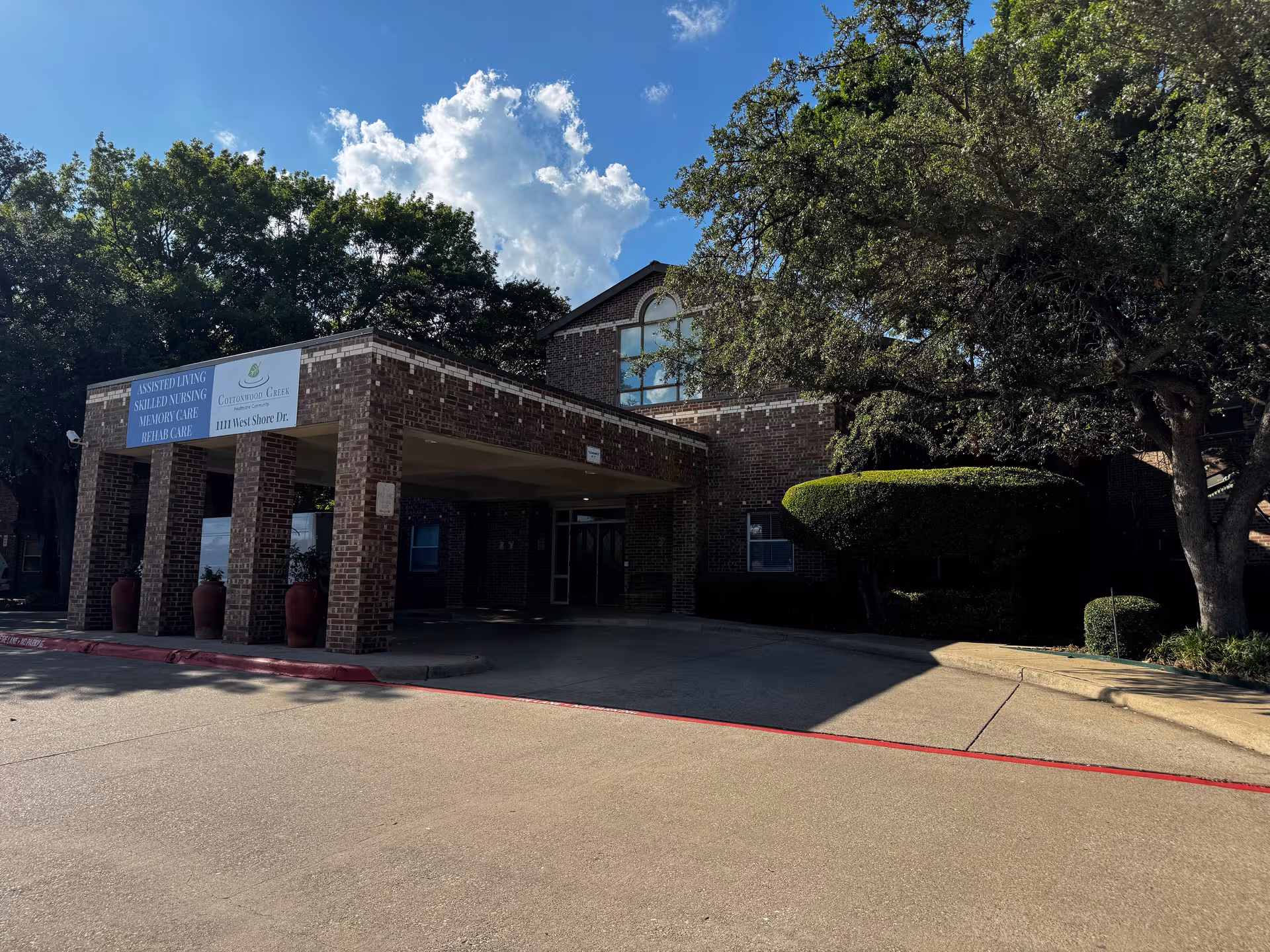 Cottonwood Creek Healthcare Community exterior: brick building with covered entrance and trees.
