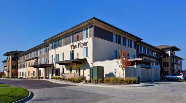 Exterior view of The Piper Assisted Living building with a driveway and landscaped entry.