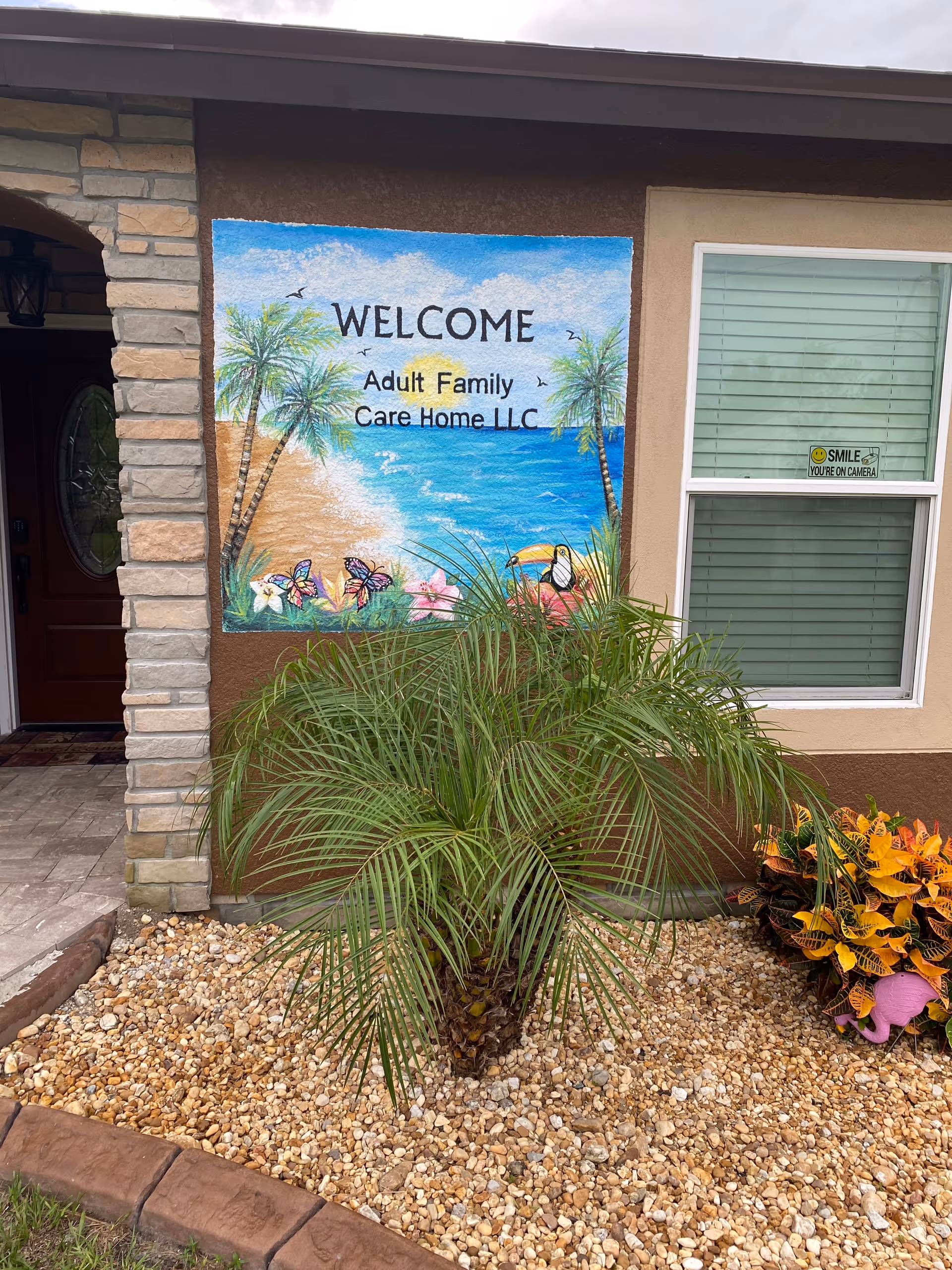 Front exterior of Frances Ransom Adult Family Care Home with a welcome mural and desert landscaping