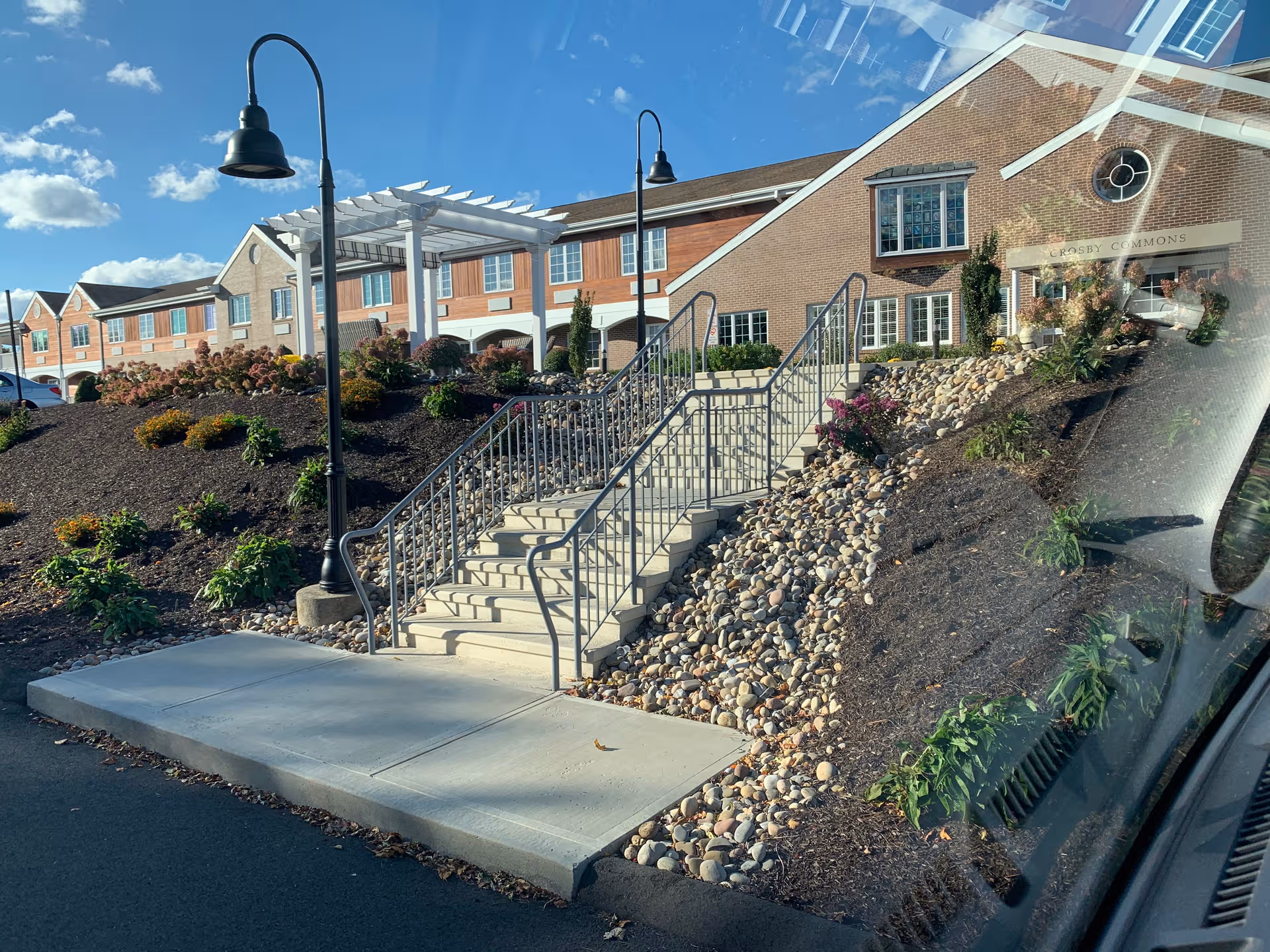 Exterior view of Masonicare at Crosby Commons senior living facility with stairs and landscaped entry.