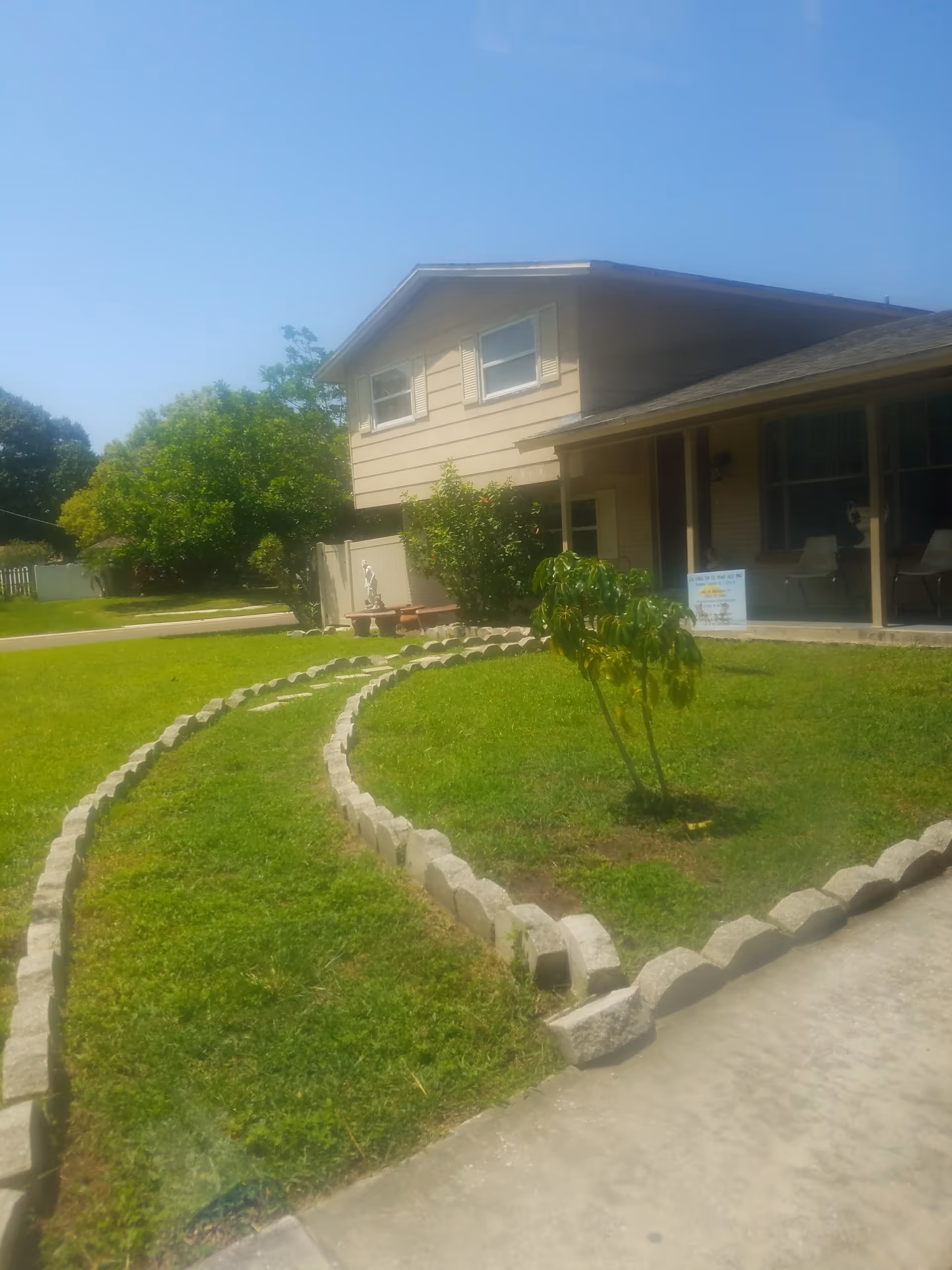 Front exterior of a beige senior living facility with curved stone garden path