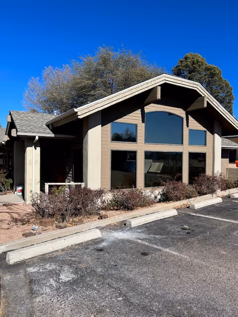 Senior living facility building with large front windows, shrubs, and a parking lot.