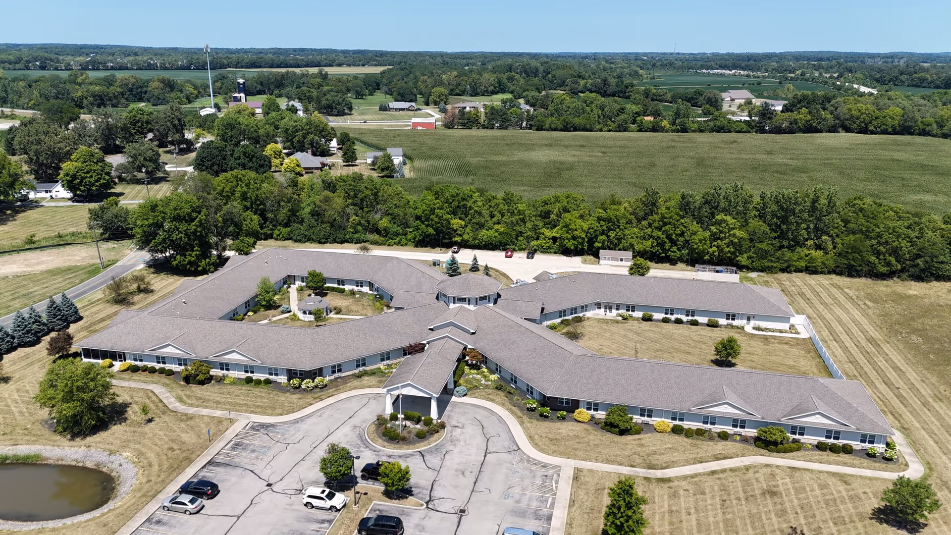 Aerial view of a large, curved, single-story senior living campus with parking.