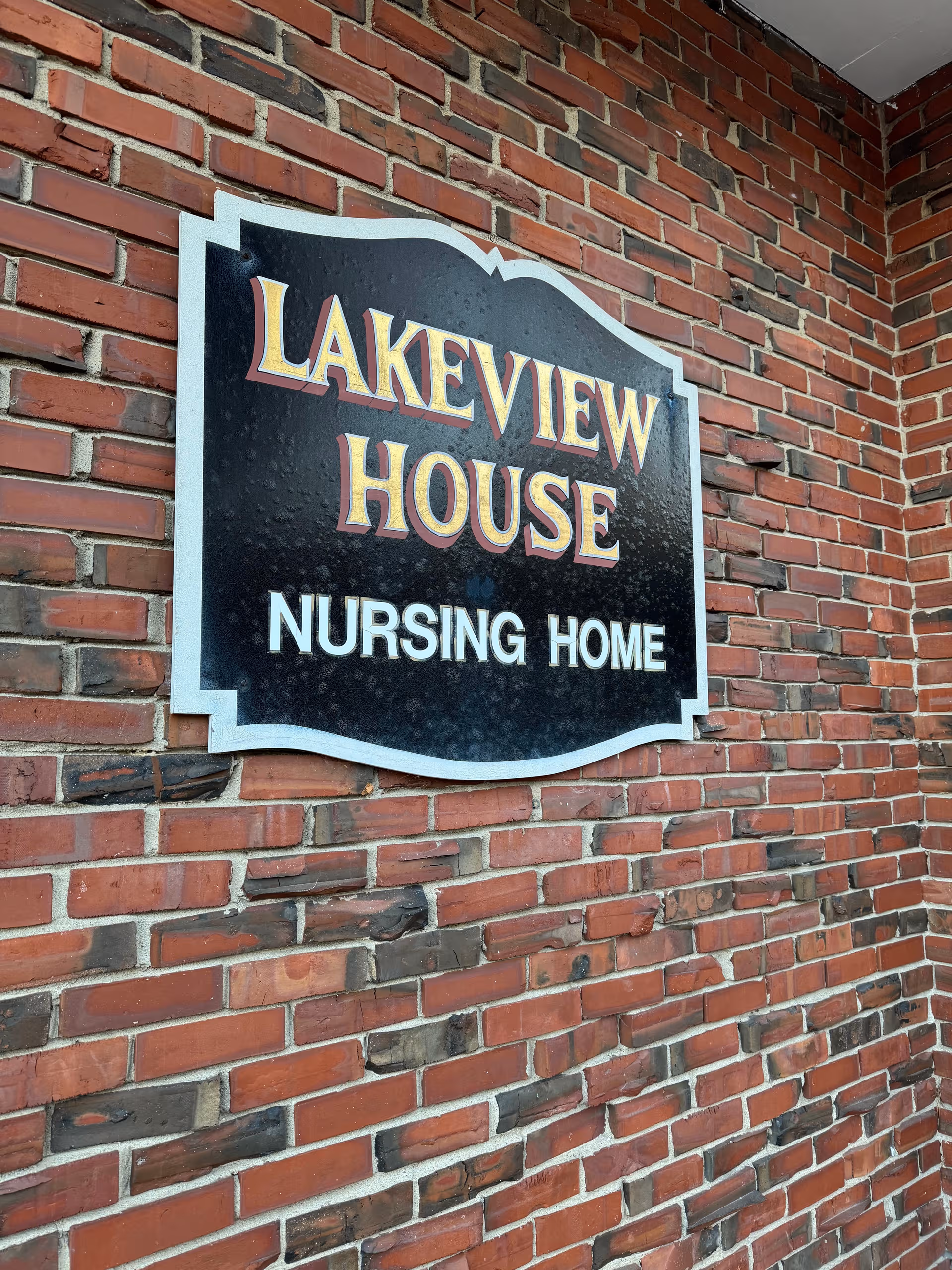 Exterior brick wall with a Lakeview House Nursing Home sign.