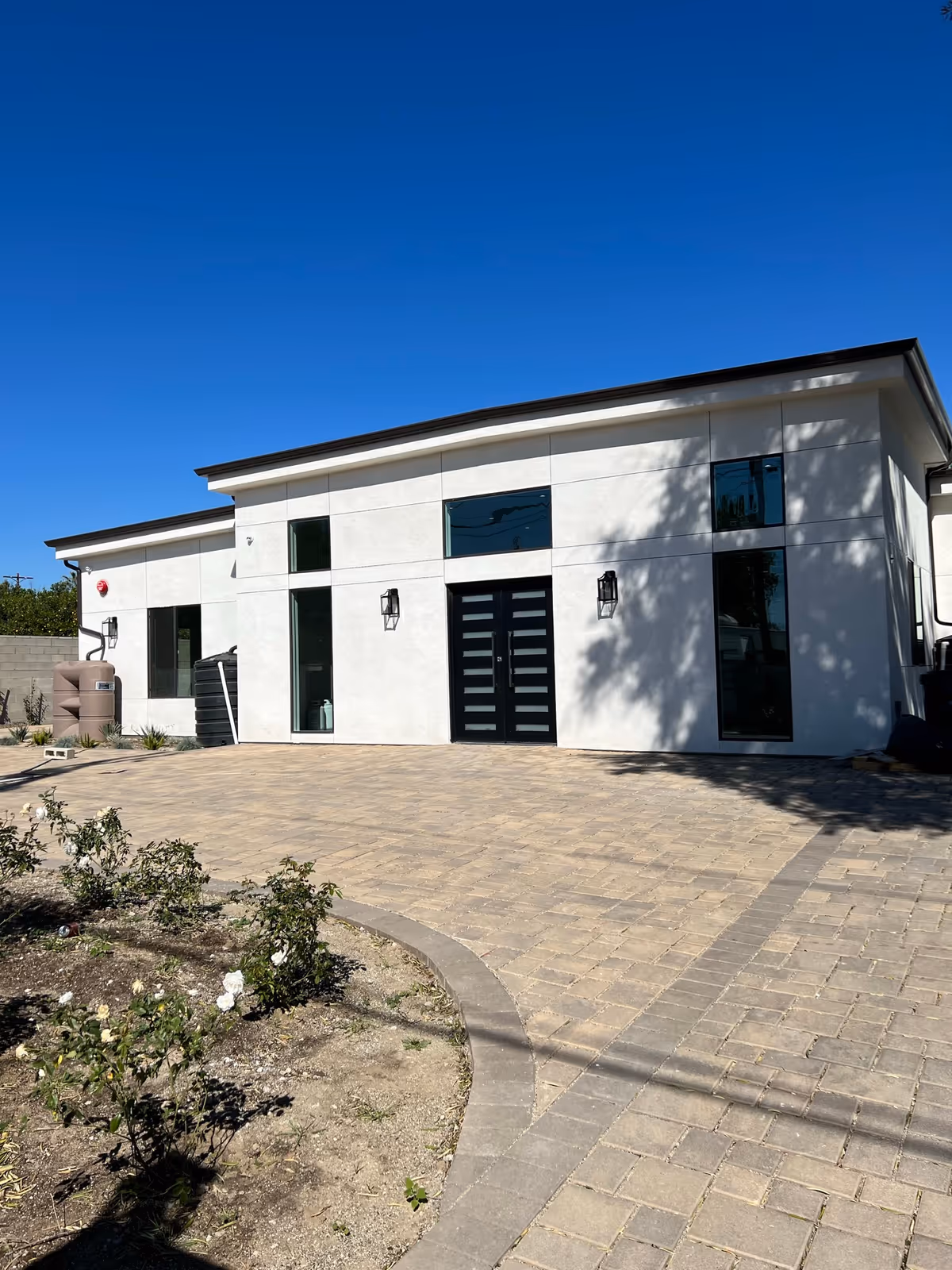 White modern senior living facility front with black double doors and paved walkway