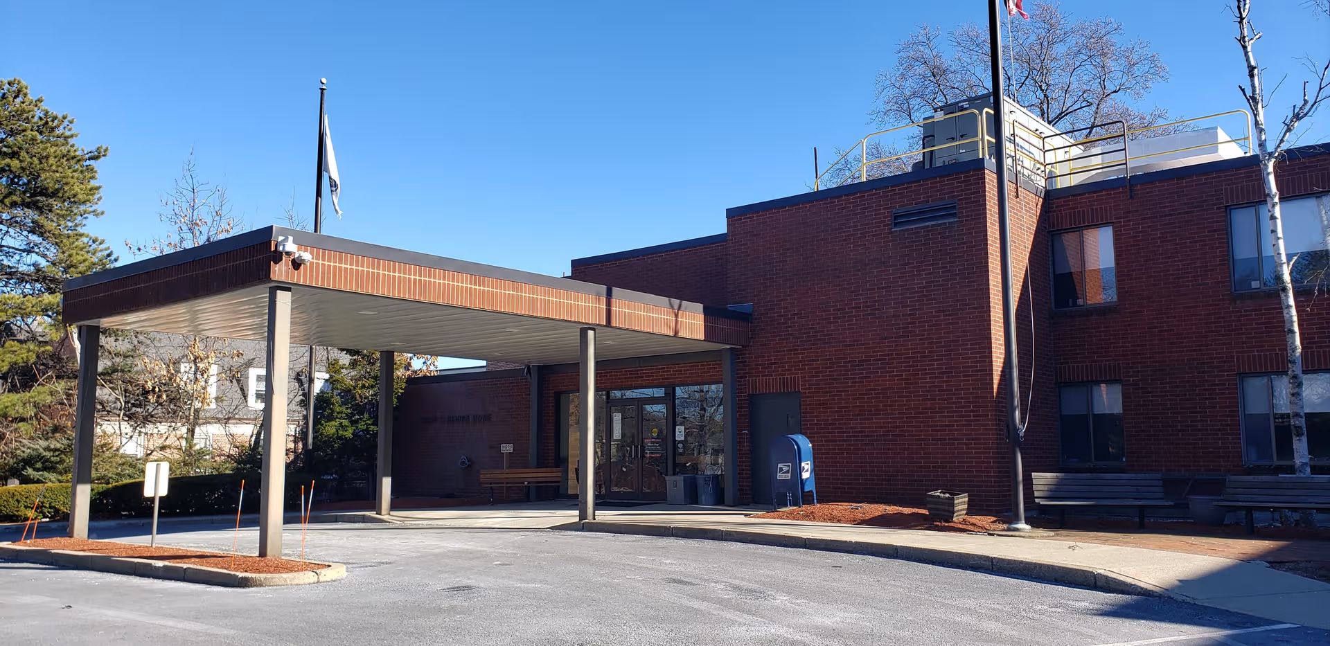 Exterior of a brick senior living facility with a covered entrance and parking area.