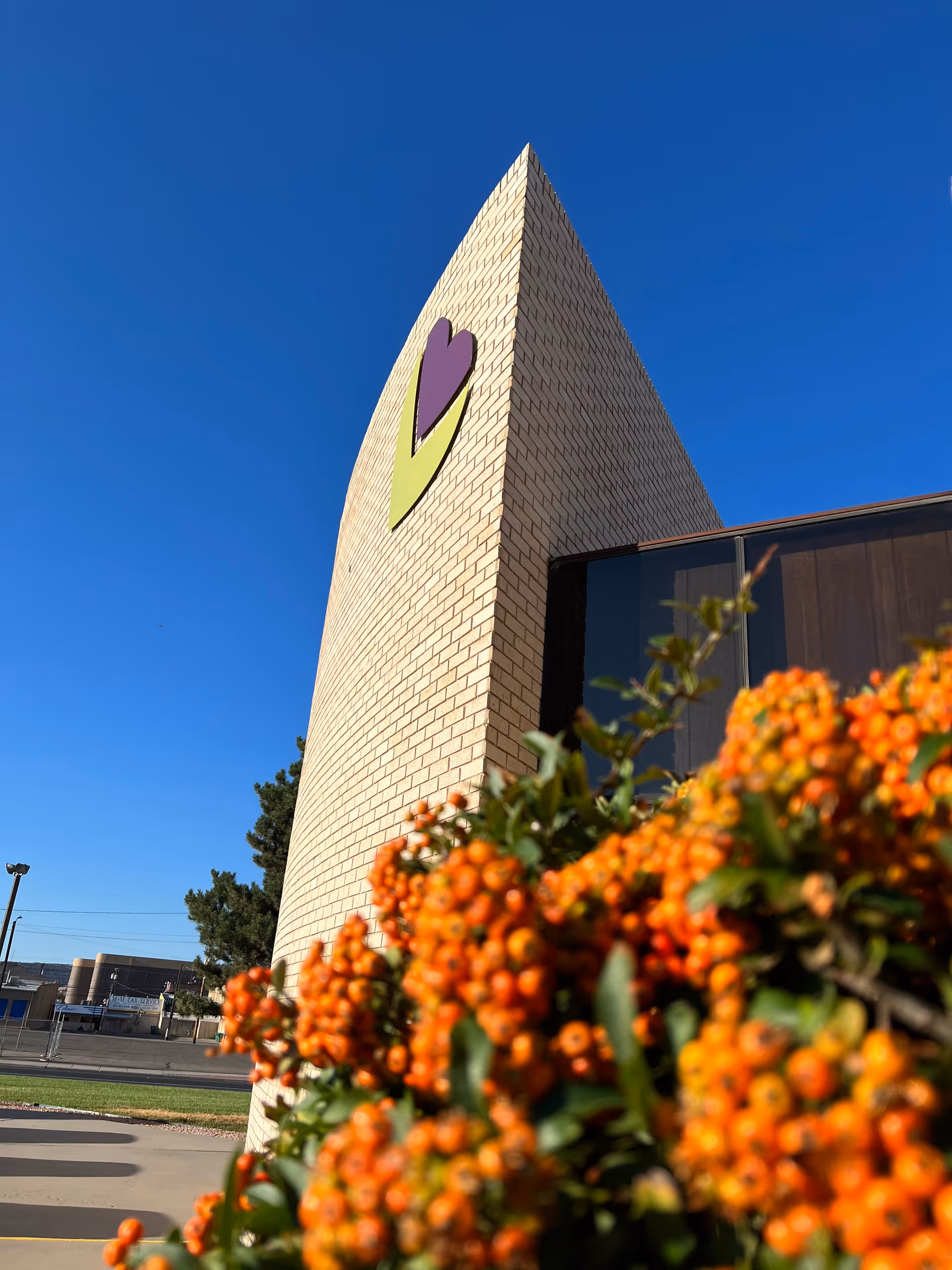 Brick building exterior with a large logo and vibrant orange flowers in foreground.