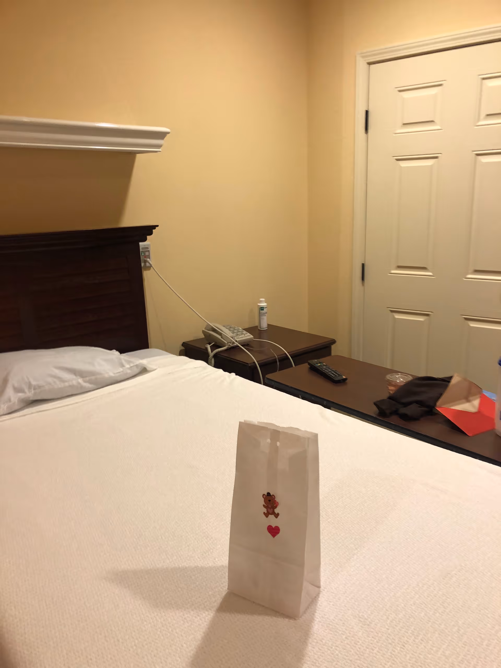 A tidy hotel-style bedroom with a bed, nightstands, and a small gift bag on the bed.