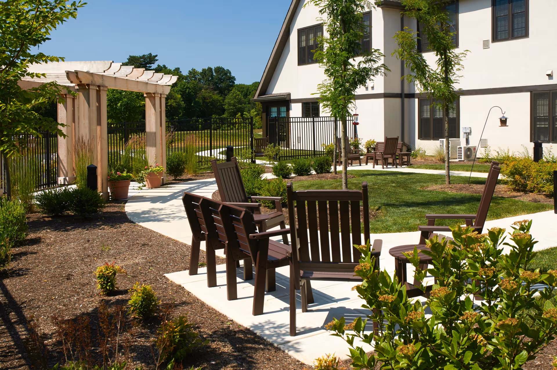 Outdoor courtyard at a senior living facility with wooden chairs and a pergola.