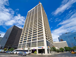 Tall modern office building along a city street under blue sky