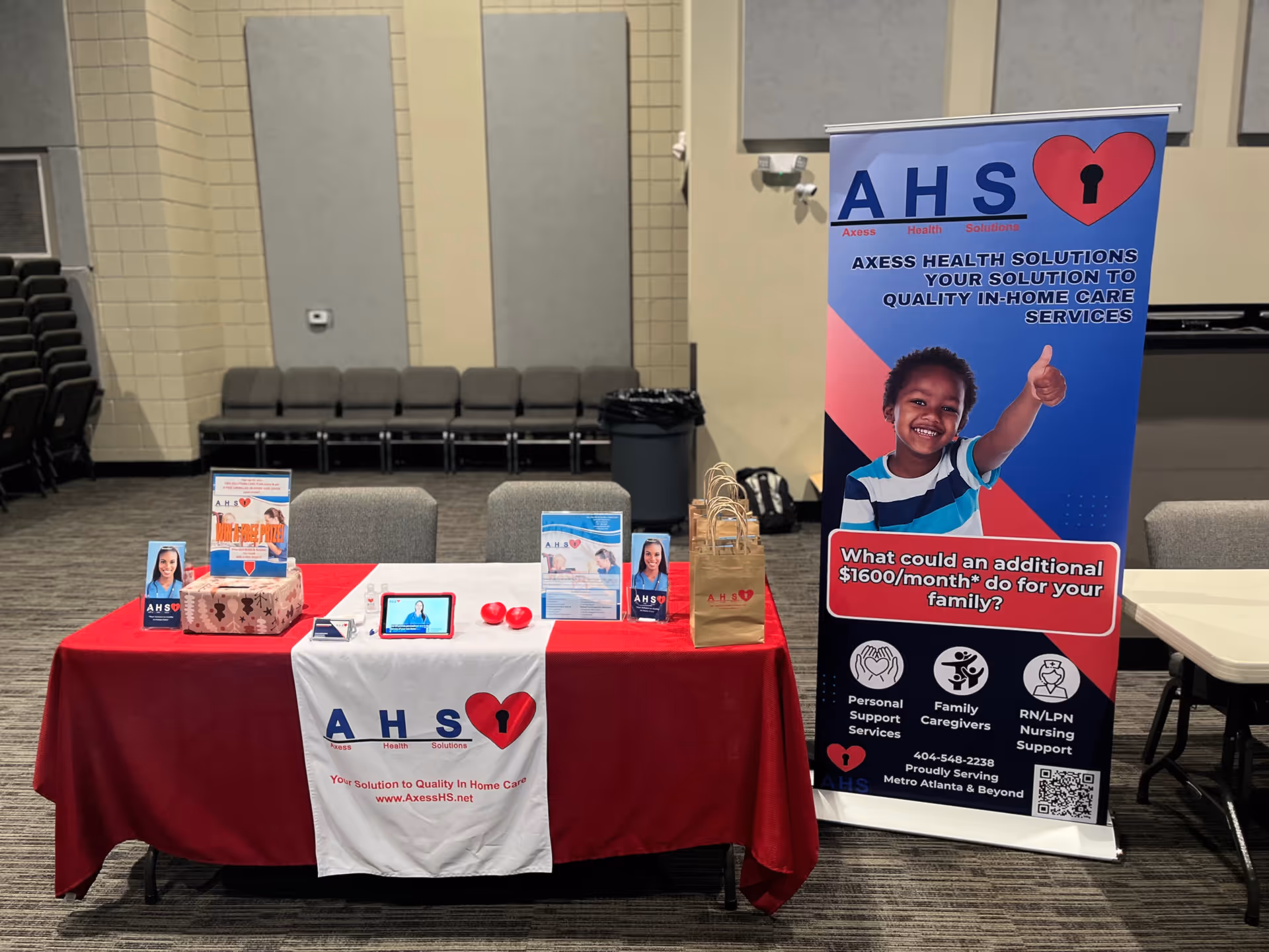 Promotional Axess Health Solutions booth with banner, table, and chairs.