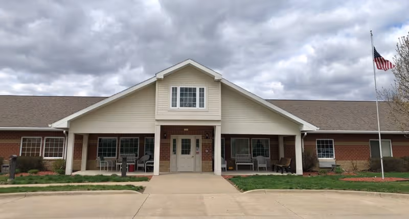 Exterior view of Courtyard Estates at Cedar Pointe entrance with covered porch and flagpole.