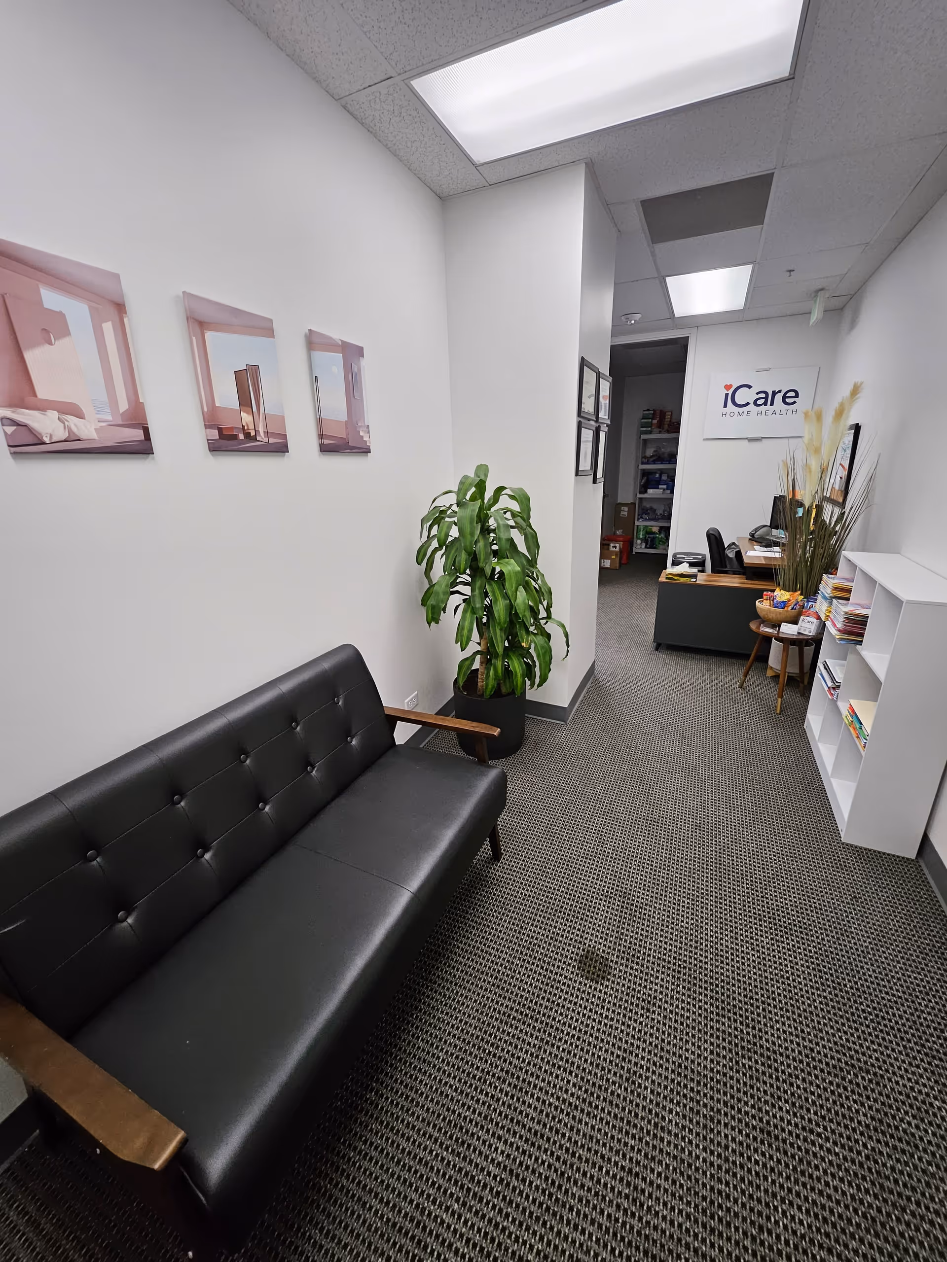 Interior waiting area of iCare Home Health with black sofa and reception desk.