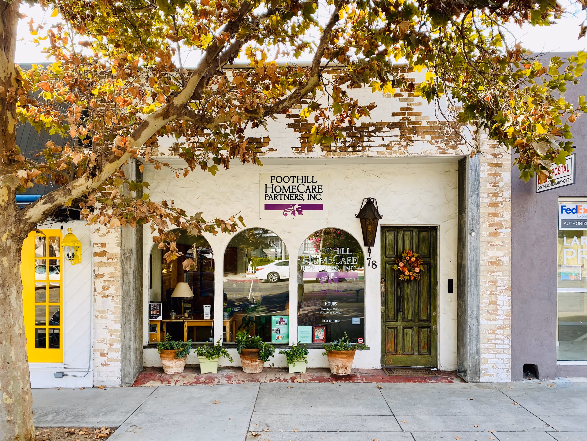 Foothill HomeCare Partners storefront with arched windows, a green door, and potted plants.