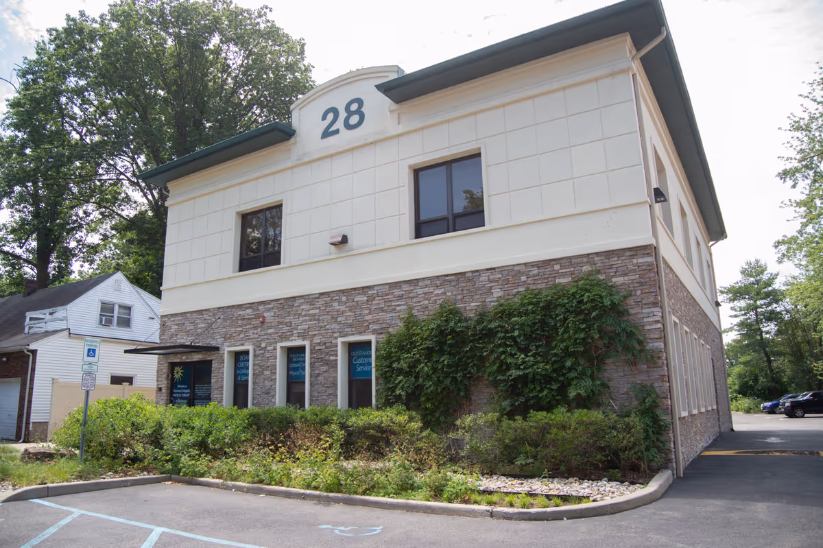 Two-story building with stone lower facade and cream upper walls, marked with number 28.