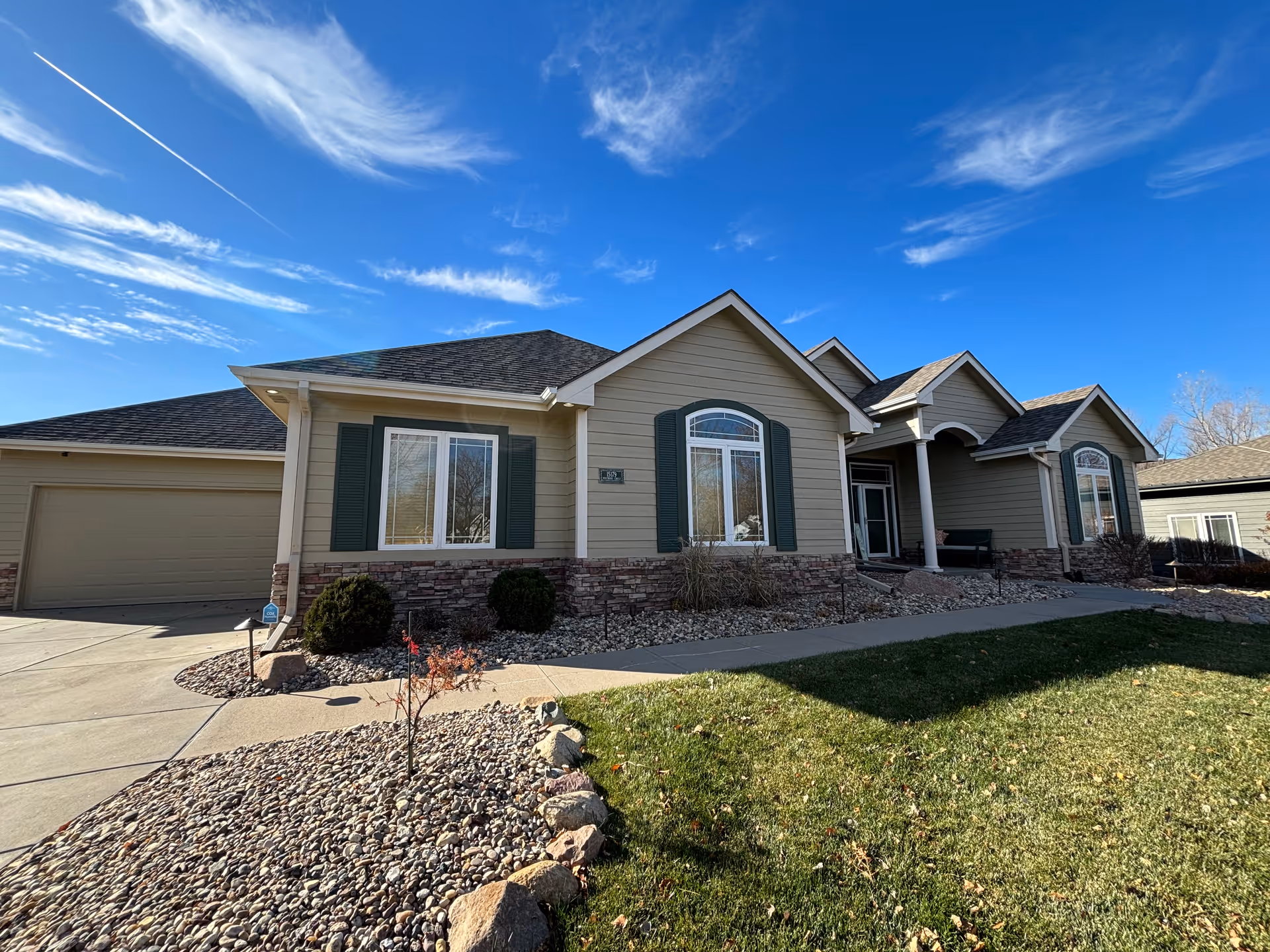 A suburban-style building front with a manicured yard and clear blue sky.