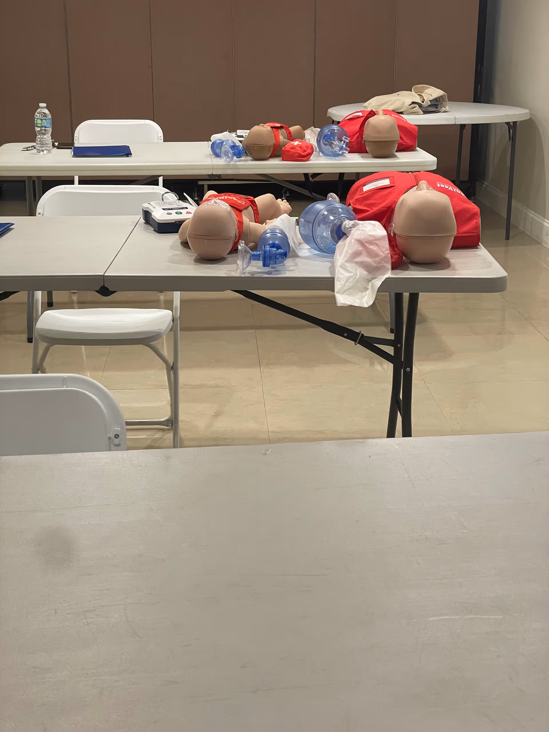 CPR training room with multiple mannequins and oxygen masks on tables.