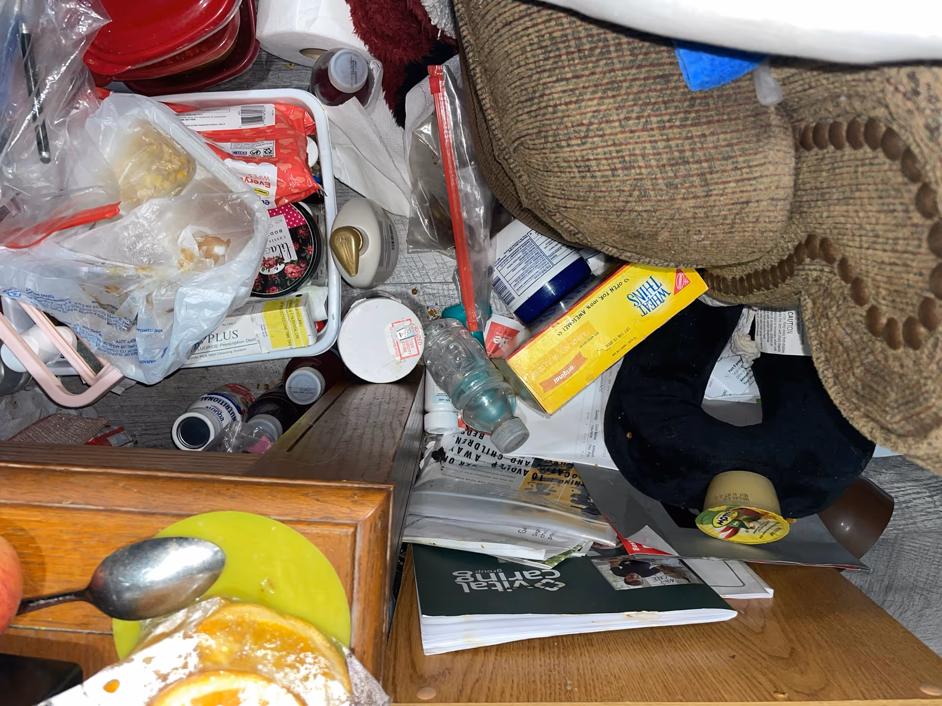 Messy kitchen counter cluttered with bags, containers, a pastry plate, and a blanket.